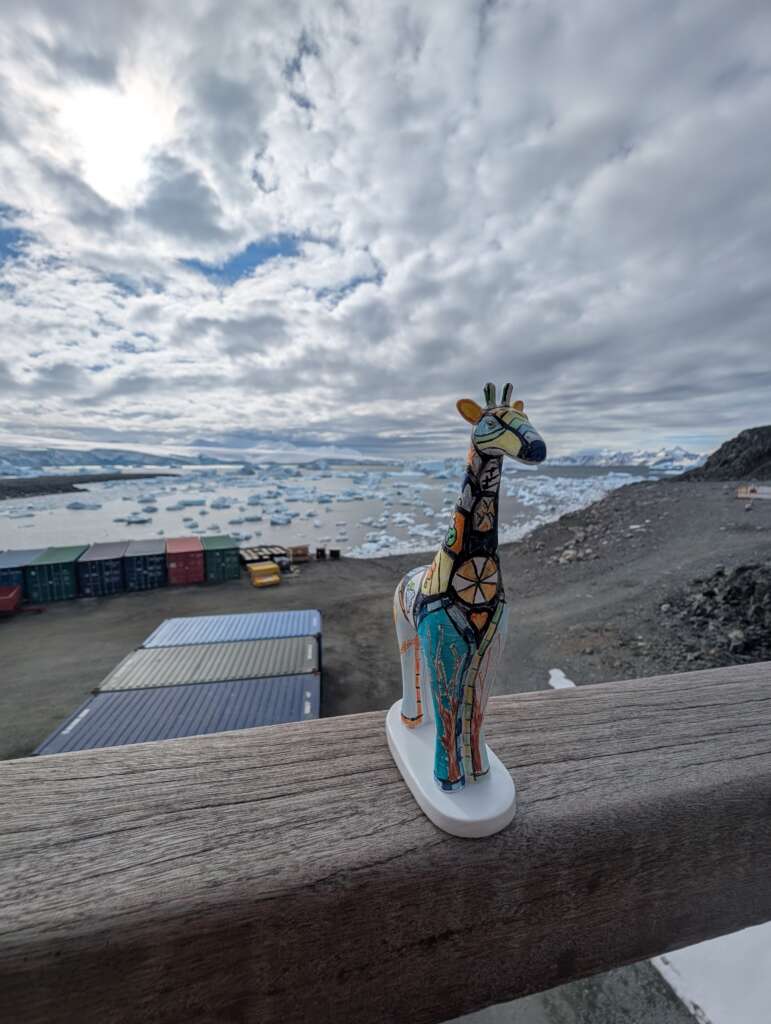 Mini giraffe statue on bannister overlooking antarctic backdrop 